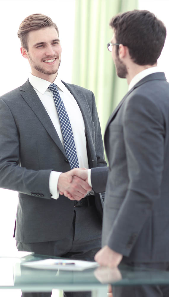 Two businessmen shaking hands and smiling.